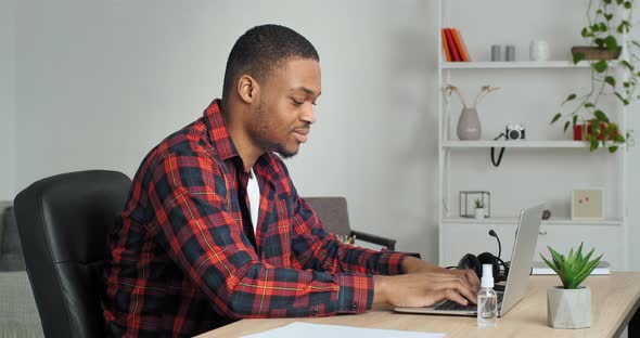 Focused Afro American Business Man Entrepreneur Typing on Laptop Computer Doing Research Sitting at alt