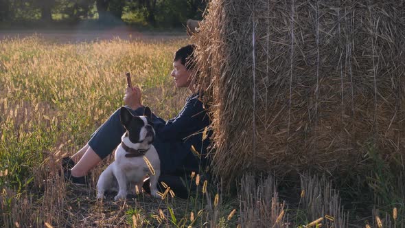 Young Woman Sitting at the Meadow with French Bulldog alt