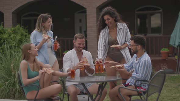 Group of happy young people cheering with cider by the pool in the garden