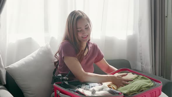 Cute woman happily zipping a suitcase smiling with her passport and credit card alt