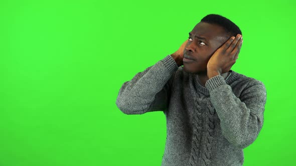 A Young Black Man Protects His Ears From a Loud Sound - Green Screen Studio alt