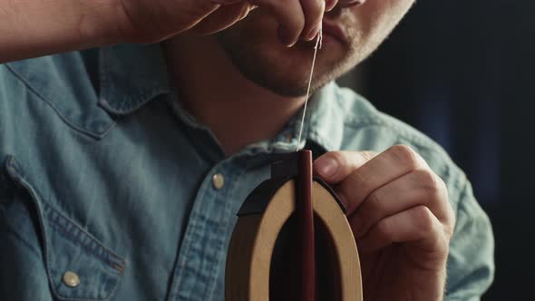 Young Man Tailor Sewing Two Pieces of Leather on Stand Closeup Using Professional Sharp Needle and alt