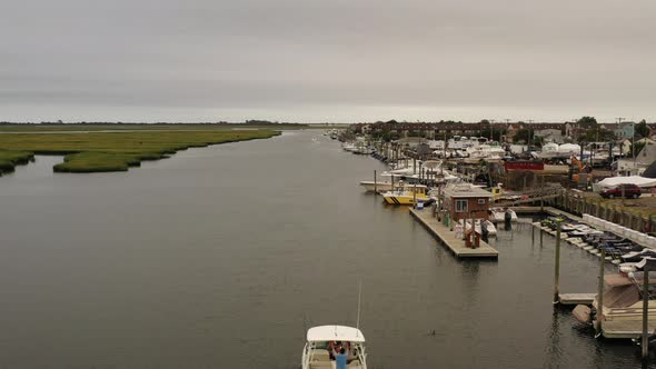 An aerial view of a small fishing boat sailing in a marsh in Freeport, NY. The drone camera hovers a alt