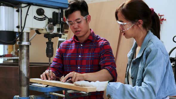 Carpenter master teach a student to use drilling  machine in university wood workshop
