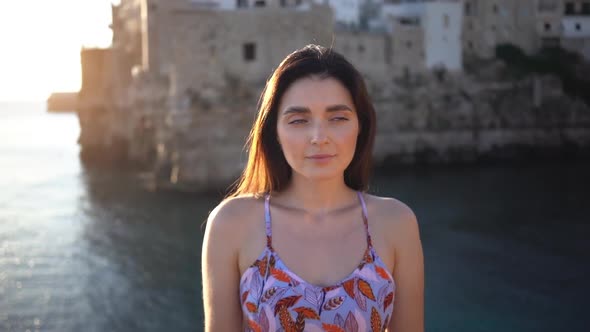 Slow motion of pretty woman posing in front of Polignano a Mare city, Italy