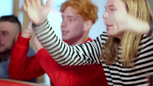 Side View of Excited Young Caucasian Man Rejoicing Victory with Friends in Bar alt
