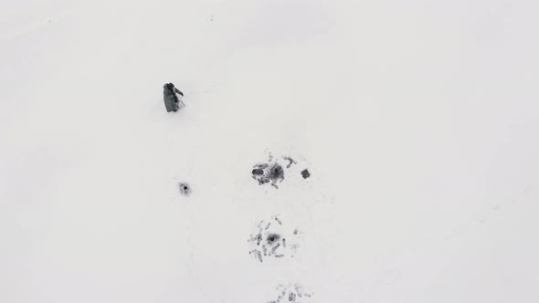 Man is drilling ice with ice drill on frozen lake alt