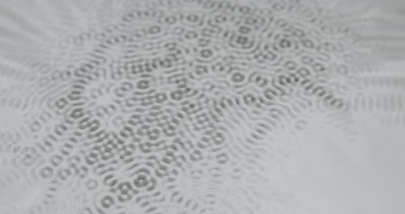 Microscopic patterns forming on water. Looking like lifeforms. Static shot of vibrating liquid. alt