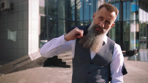 Portrait of Handsome Bearded Mature Man in Suit Outdoors on Modern Building Background During Sunny alt