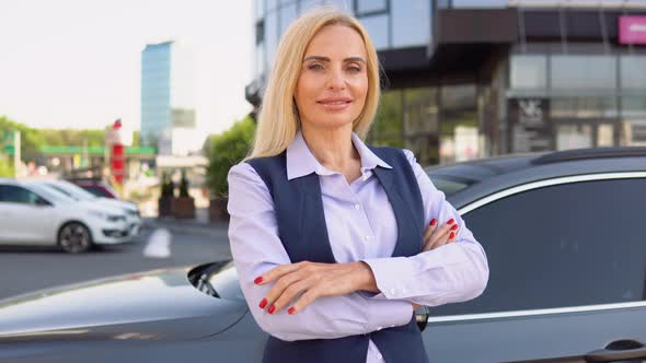 Portrait of a Confident 50 Years Woman Standing Near Her Car in a Business Suit Against the alt