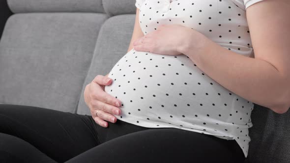 Pregnant Woman with Red Apple on Sofa