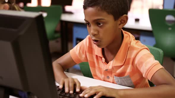 Schoolboy studying on personal computer in classroom alt