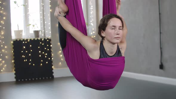 Young Woman Hanging on the Yoga Hammock and Holding Her Ankles alt