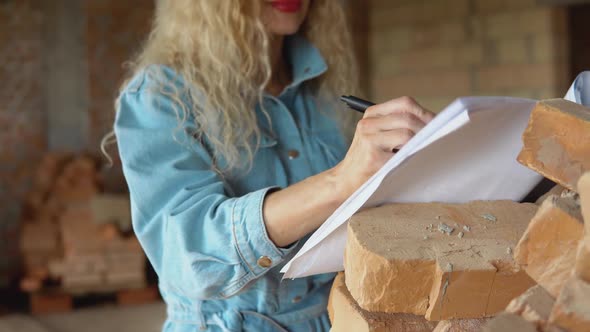 Female Architect Reads the Architectural Plan for the Construction of the House and Makes Marks in alt