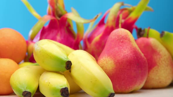 Fresh Healthy Fruits Apples Oranges Bananas Pears Dragon Fruit on a Blue Background Lie on a White alt