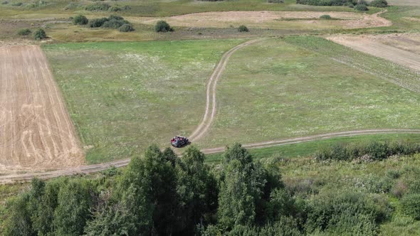 Aerial View of an Off-Road Vehicle Driving Down a Pathway in Rural Farmland alt