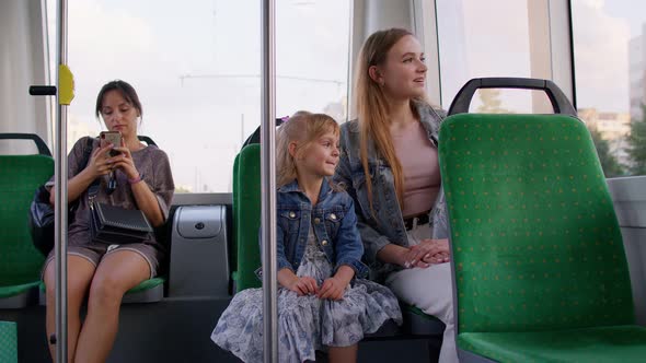 Family Rides in Public Transport Woman with Little Child Girl Sit Together and Look Out Window Tram alt
