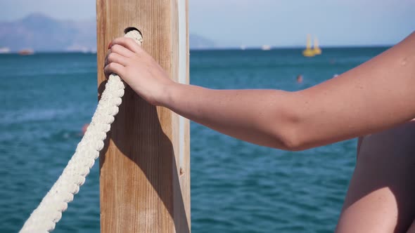Girl Holding Rope On Pier. Woman Hand Holding Rope And Relish Holiday Vacation At Sea. Mediterranean alt