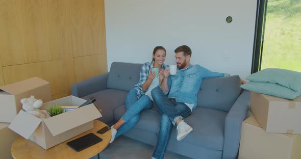 Panning Waist-up Shot of Pleased Smiling Caucasian Husband and Wife Relaxing and Drinking Tea alt