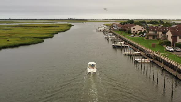 An aerial view of a fishing boat sailing in a marsh in Freeport, NY. The camera dolly in, then truck alt