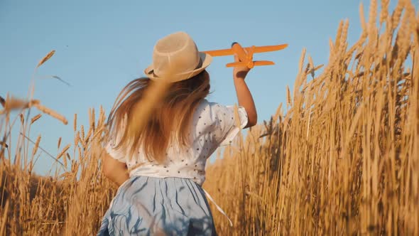 Happy Girl Child Run on Wheat Field with an Airplane alt