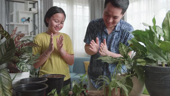 Father And Daughter Transplanting Plant At Home alt