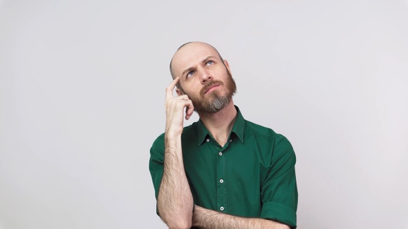 Portrait of serious bearded man thinking or remembering, isolated over white background