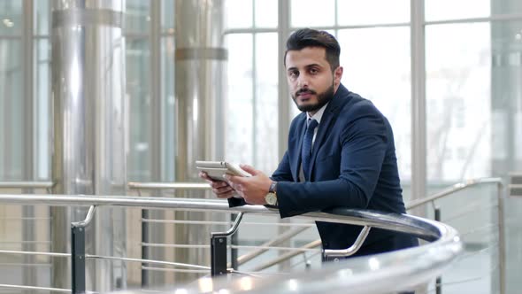 Arabian businessman watching webinar on tablet computer indoor