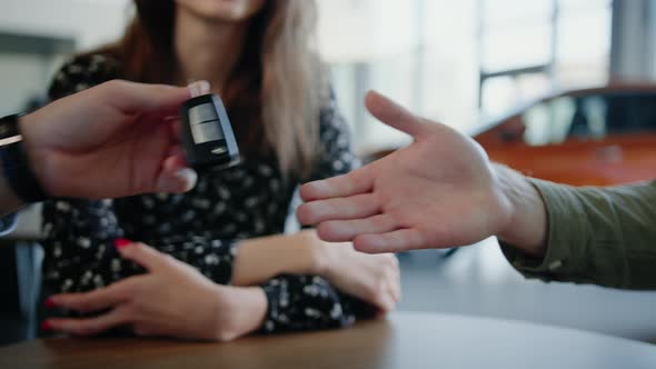 Closeup of the Hand of the Dealership Manager Who Gives the Customer the Keys to a New Car alt