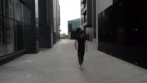 A Man Walks Down the Alley Between the Buildings.