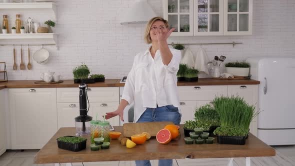 Young Woman Cuts a Kiwi to Make a Cocktail with Microgreens and Sprouted Wheat alt