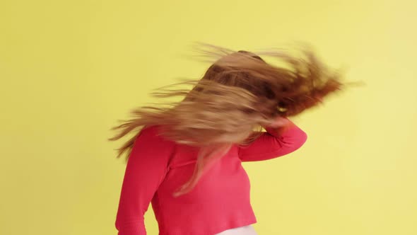 cheerful pretty woman is actively dancing  on an isolated yellow background