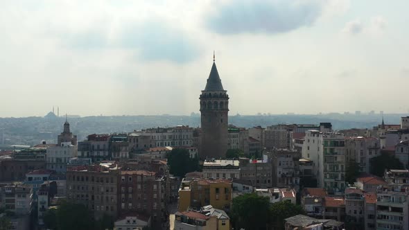 Aerial drone flying upwards revealing a silhouette of buildings surrounding Galata Tower in Taksim I alt