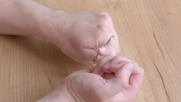 Close Up of a Man Using a Nail Scissors to Cut His Nails