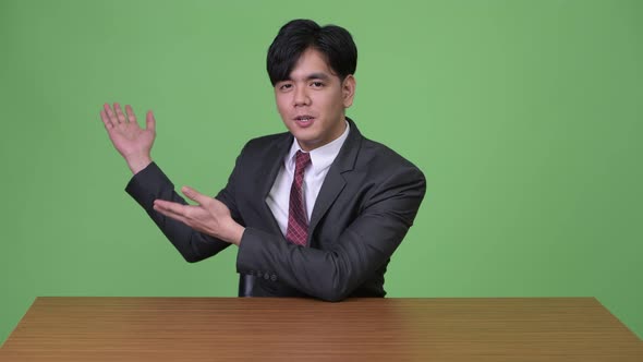 Young Handsome Asian Businessman Against Green Background alt
