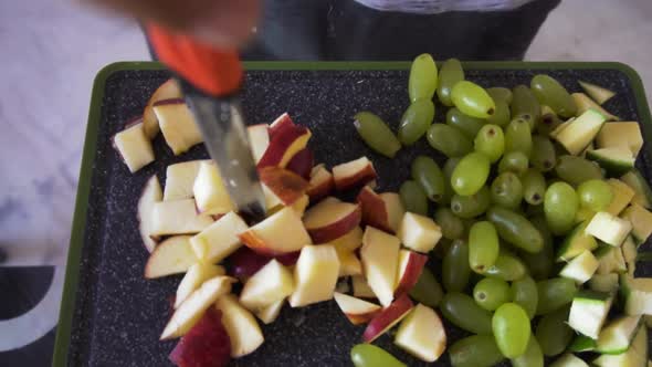 Young man making fruit salad. man holding knife on the chopping board alt