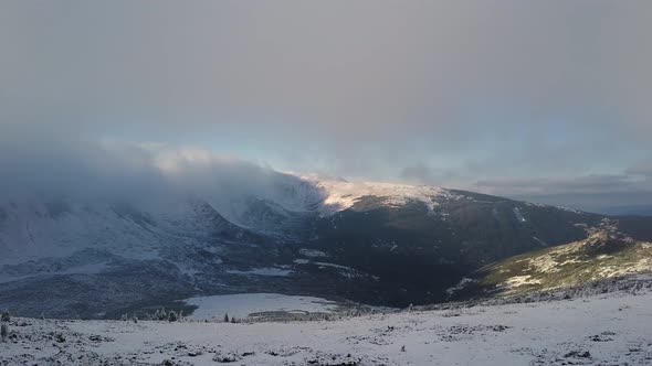 Aerial view of moody snow cowered mountain hills in cold winter weather. alt