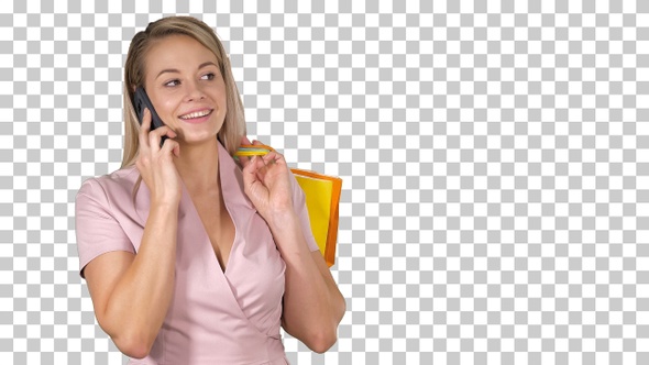 Young woman with shopping bags talking on mobile phone alt