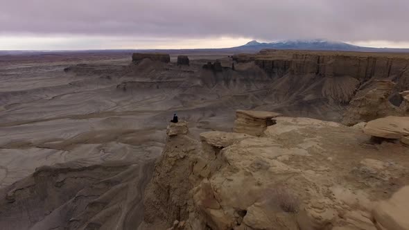 Aerial view flying past person sitting on rock at Moonscape overlook alt