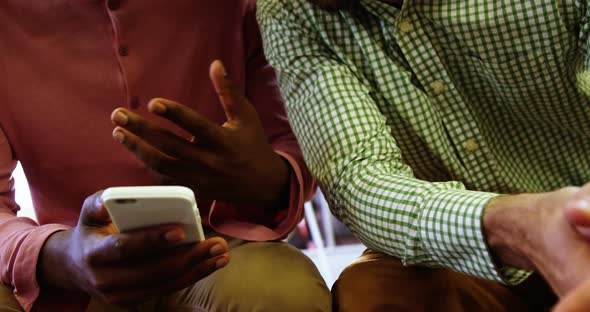 Business executives discussing over mobile phone alt