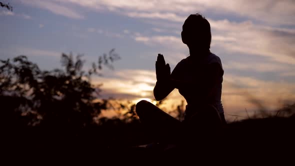 Silhouette of a Christian woman praying at sunset, outdoors alt