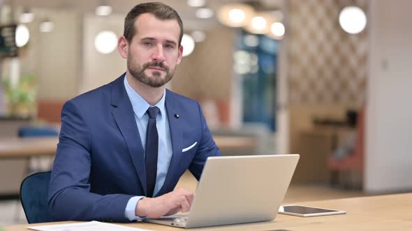 Serious Businessman with Laptop Looking at Camera alt