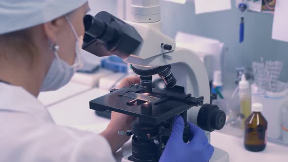 Lab Technician Looking Through a Microscope alt