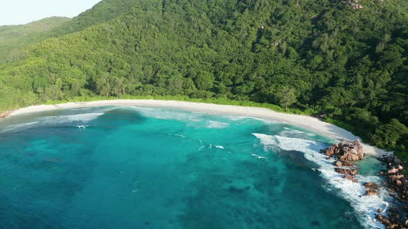 Aerial dolly descent over emerald lagoon Anse Cocos beach, La Digue alt