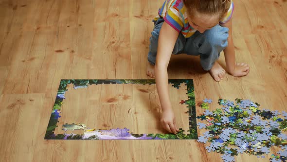 A Beautiful Girl Collects Puzzle Puzzles Sitting on a Wooden Floor