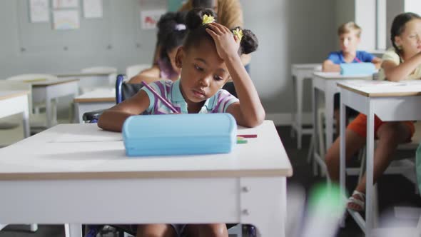 Video of focused african american girl sitting at desk in classroom alt