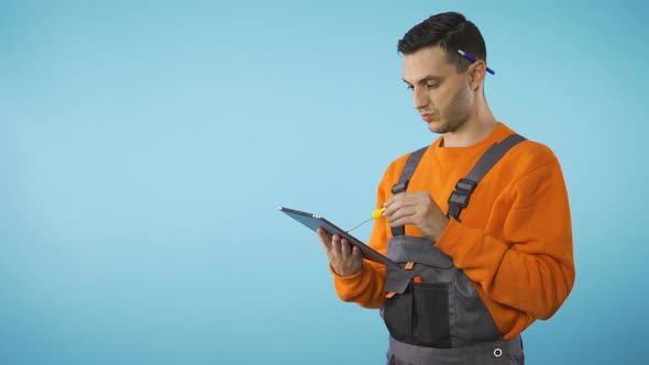 Architect or Construction Worker Taking Notes on Tablet Using Screwdriver alt
