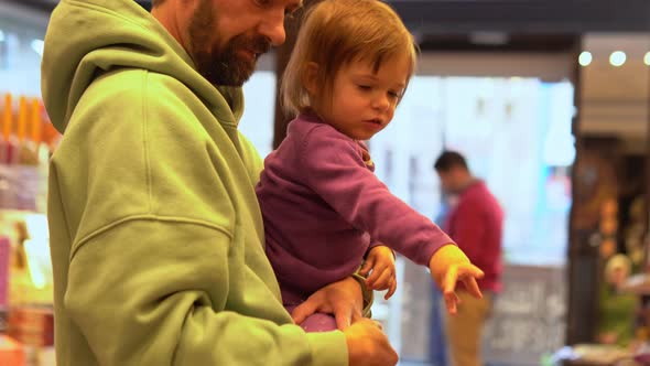 Little Girl is Choosing Sweets with Dad in Candy Shop