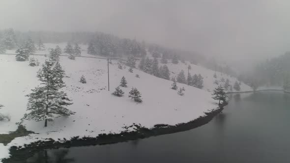 Misty Lake Bay During Blizzard Snowfall Winter Aerial Drone Shot Still Water Snowy Forest