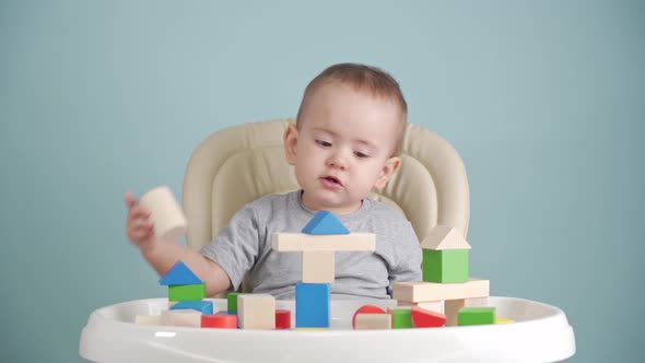 A kid of 15-25 months is learning to build a tower of wooden cubes alt